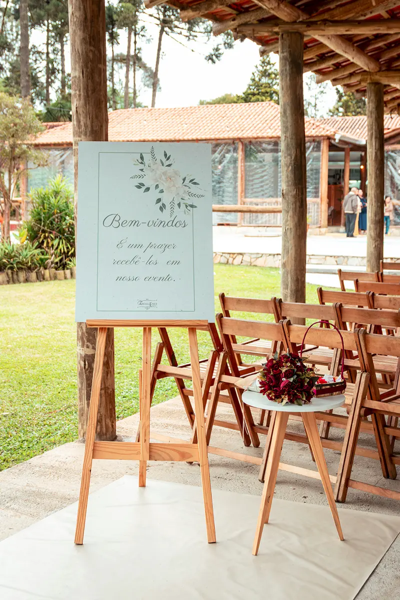 Placa de boas-vindas no cavalete, ao lado das cadeiras da cerimônia