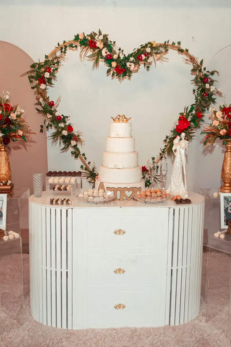 Bolo de quatro andares diante de um coração de flores