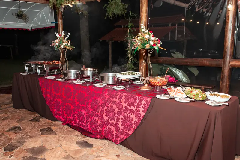 Buffet à noite com toalha vermelha e arranjos