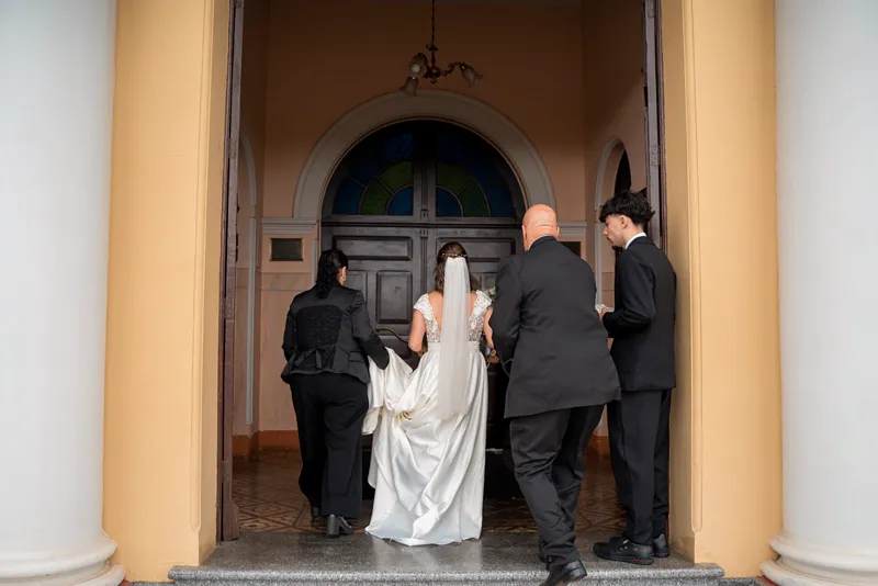 Na porta da igreja, a equipe da Excellence segura a cauda do vestido enquanto a noiva entra com o pai